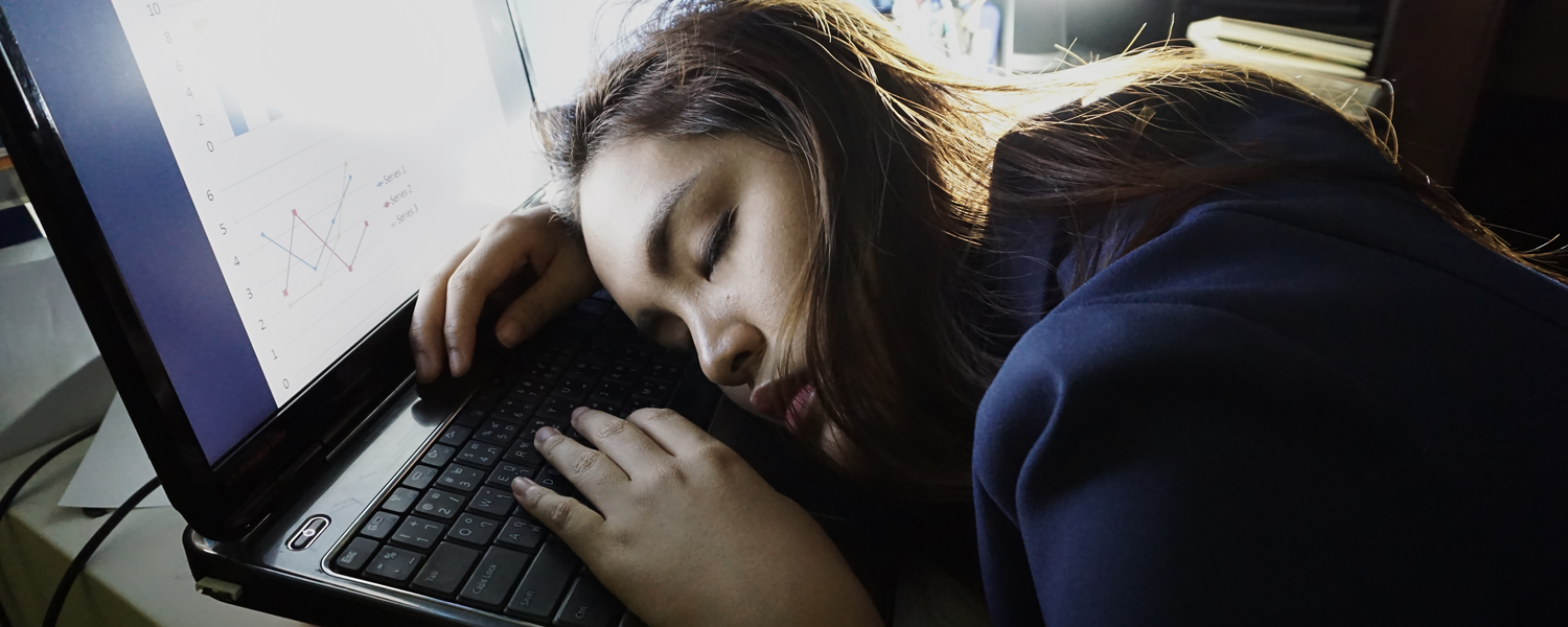 Jovem cansada dormindo em cima do computador