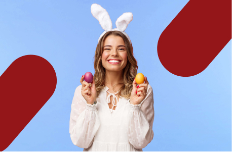 Mulher vestindo orelha de coelho e segurando dois ovos de Páscoa. A imagem ilustra o artigo "mensagens de páscoa para clientes".